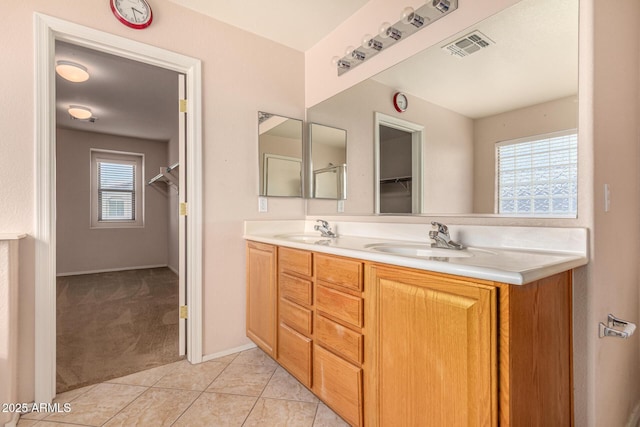 bathroom featuring tile patterned flooring, visible vents, double vanity, and a sink