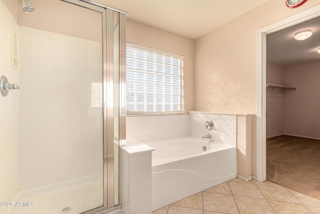 bathroom with tile patterned floors, a walk in closet, a stall shower, and a bath