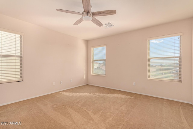 empty room with visible vents, light carpet, baseboards, and a ceiling fan