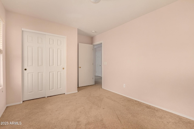 unfurnished bedroom with a closet, carpet floors, and baseboards