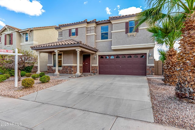 mediterranean / spanish home with a tiled roof, concrete driveway, stucco siding, stone siding, and an attached garage