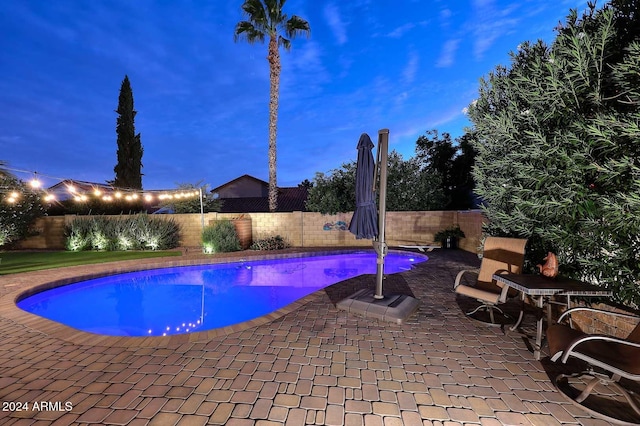 pool at dusk with a patio area