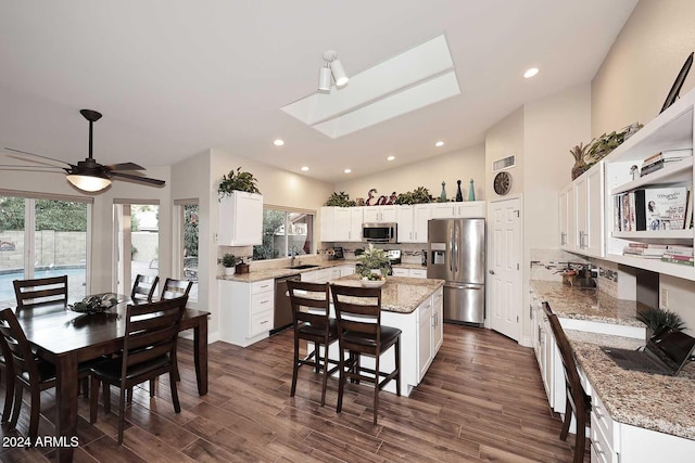 kitchen with white cabinets, stainless steel appliances, dark hardwood / wood-style floors, and a center island