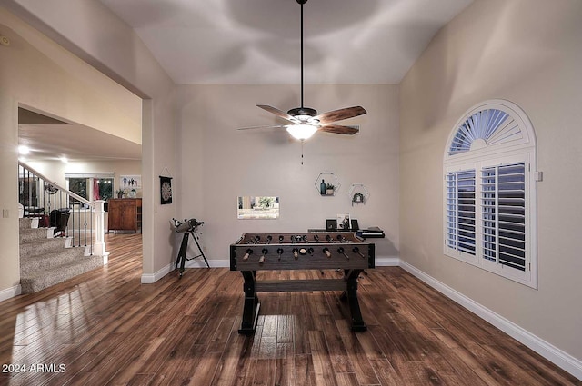 rec room featuring dark wood-type flooring, ceiling fan, and a towering ceiling