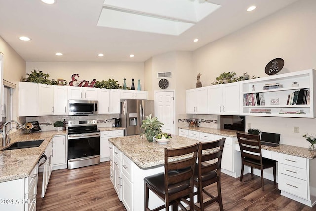 kitchen featuring appliances with stainless steel finishes, dark wood-type flooring, sink, and a center island