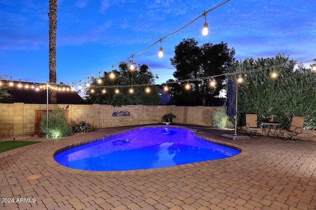 pool at dusk featuring a patio area