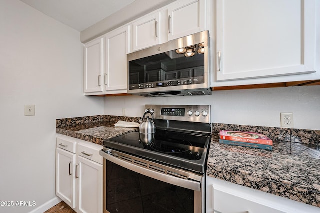 kitchen featuring stainless steel appliances, dark countertops, white cabinetry, and baseboards