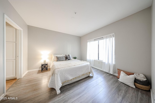 bedroom featuring light wood finished floors and baseboards