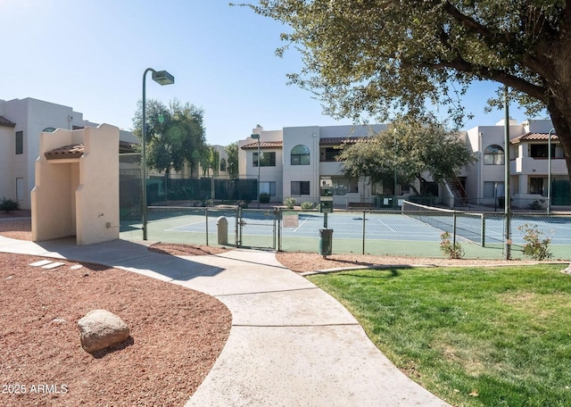 exterior space with a gate, a tennis court, and fence