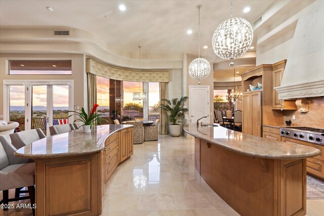6621 N Arizona Biltmore Cir, Phoenix, AZ 85016 - kitchen featuring a large island, a chandelier, premium range hood, stainless steel gas cooktop, and a kitchen bar