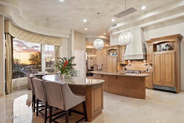 6621 N Arizona Biltmore Cir, Phoenix, AZ 85016 - kitchen featuring open shelves, a center island with sink, custom range hood, a chandelier, and recessed lighting