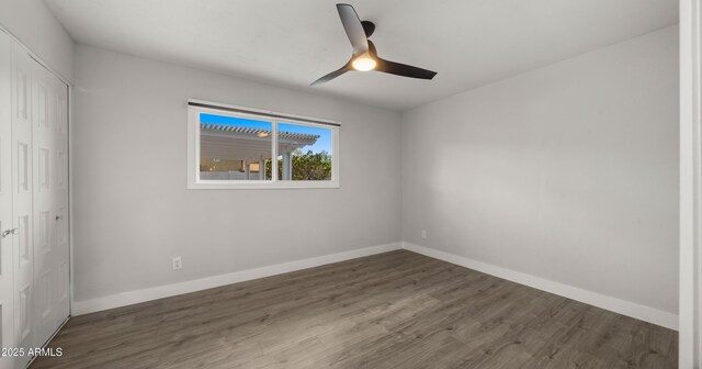 empty room with baseboards, a ceiling fan, and wood finished floors