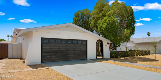 single story home with fence, stucco siding, a gate, concrete driveway, and an attached garage