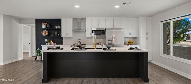 kitchen with light countertops, stainless steel appliances, visible vents, and wall chimney exhaust hood