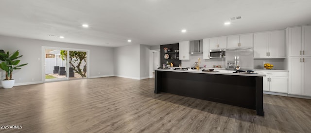 kitchen with recessed lighting, wood finished floors, wall chimney range hood, and stainless steel appliances