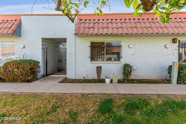 view of property featuring a tile roof and stucco siding