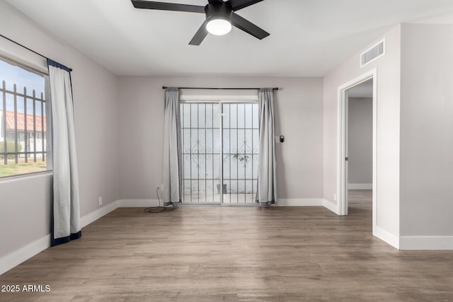 unfurnished room with a ceiling fan, visible vents, light wood-style flooring, and baseboards