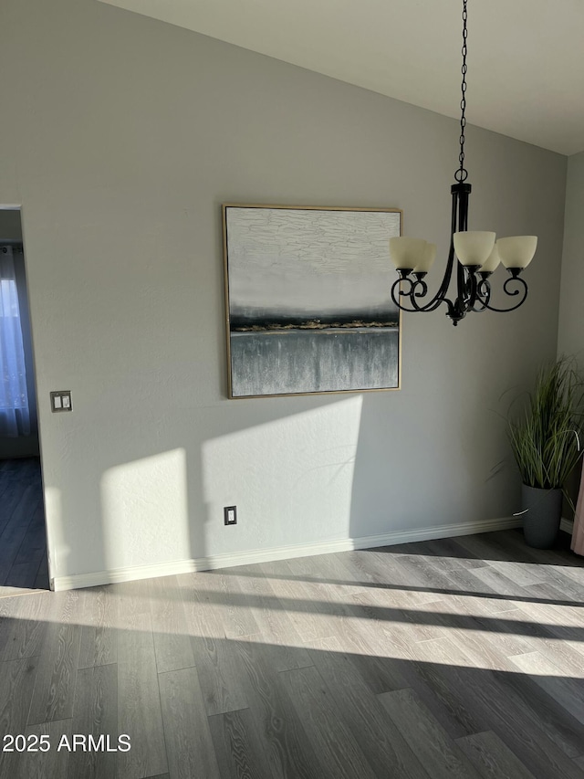 unfurnished dining area with vaulted ceiling, a chandelier, and wood-type flooring