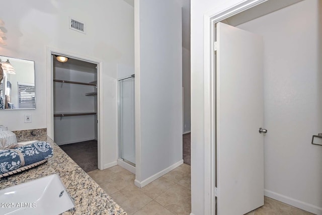 bathroom featuring tile patterned flooring, walk in shower, and vanity