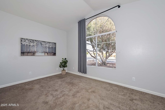 spare room featuring carpet flooring and vaulted ceiling