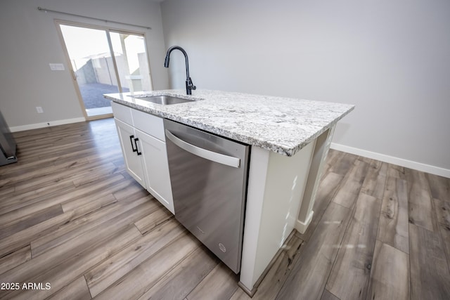 kitchen with sink, white cabinetry, a kitchen island with sink, light stone counters, and stainless steel dishwasher