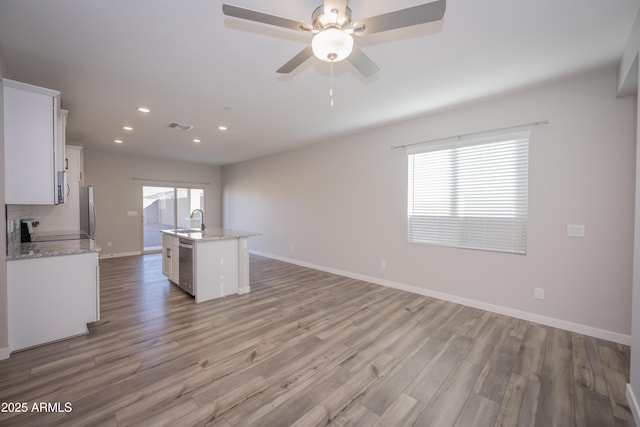 kitchen featuring dishwasher, sink, white cabinets, stove, and a center island with sink