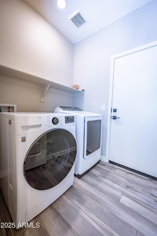 washroom with separate washer and dryer and light wood-type flooring