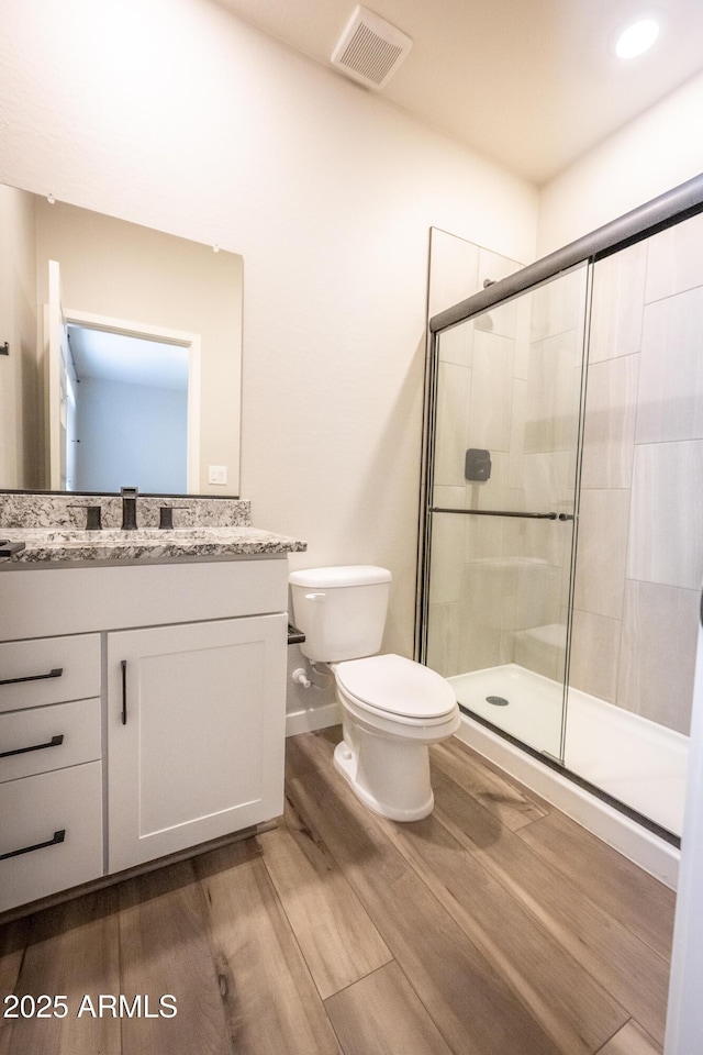 bathroom featuring hardwood / wood-style flooring, vanity, toilet, and an enclosed shower