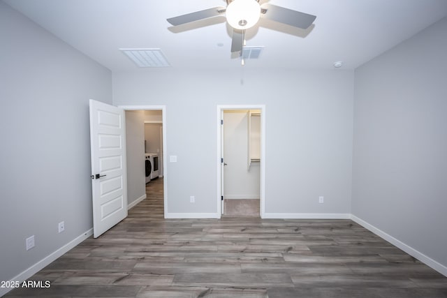 unfurnished bedroom with wood-type flooring, washer / dryer, a spacious closet, and ceiling fan