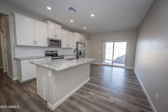 kitchen featuring sink, white cabinetry, tasteful backsplash, a center island with sink, and stainless steel appliances