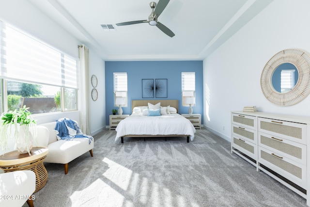 bedroom featuring ceiling fan, light colored carpet, and multiple windows