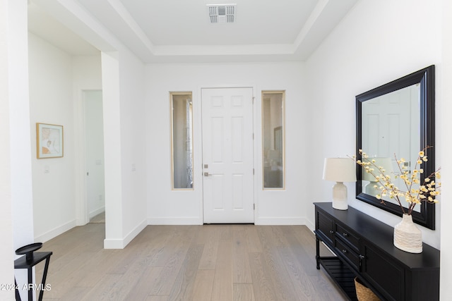 foyer entrance with a tray ceiling and light hardwood / wood-style flooring