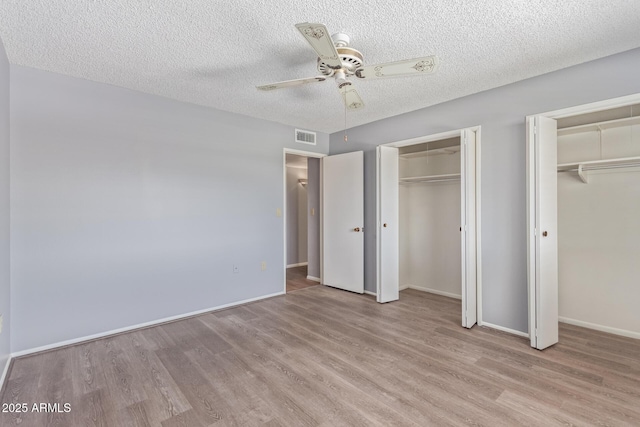 10236 N 105th Dr, Sun City, AZ 85351 - unfurnished bedroom with multiple closets, wood finished floors, baseboards, a textured ceiling, and a ceiling fan