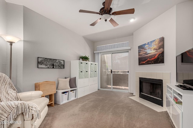 living area featuring a ceiling fan, carpet flooring, and a fireplace