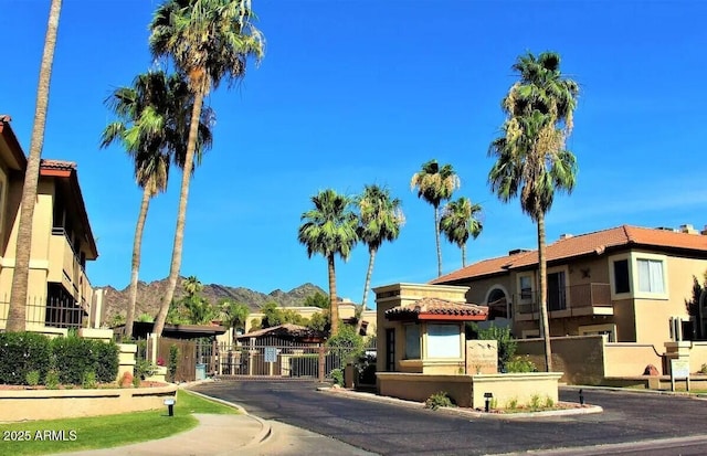 view of road featuring a gate, curbs, a mountain view, and a gated entry