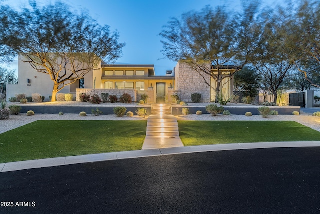 view of front facade featuring a front lawn, stone siding, and stucco siding