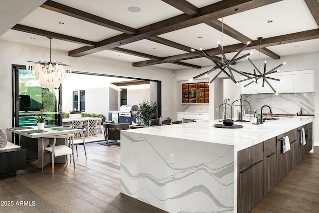 kitchen with a spacious island, a chandelier, beamed ceiling, hardwood / wood-style floors, and modern cabinets