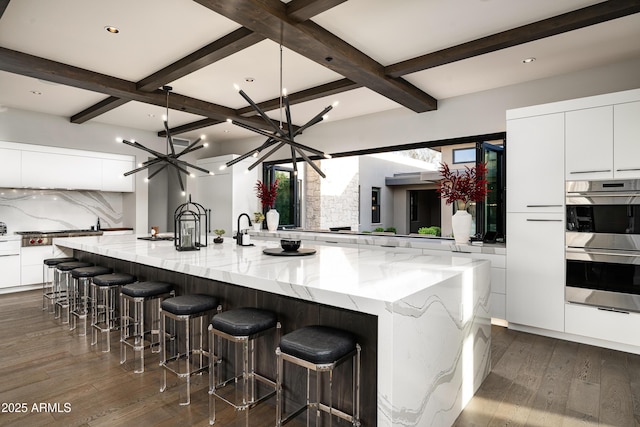 kitchen featuring a large island, modern cabinets, tasteful backsplash, double oven, and white cabinets