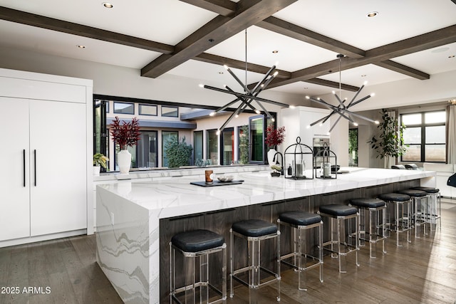 kitchen with beam ceiling, dark wood-type flooring, white cabinetry, a notable chandelier, and modern cabinets