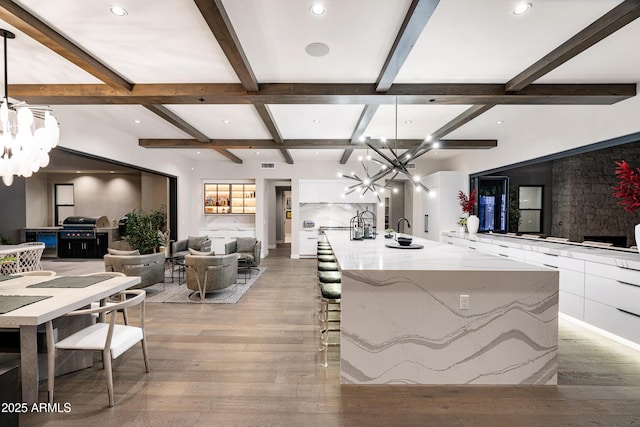 kitchen featuring a chandelier, a kitchen bar, light wood-style flooring, white cabinetry, and modern cabinets