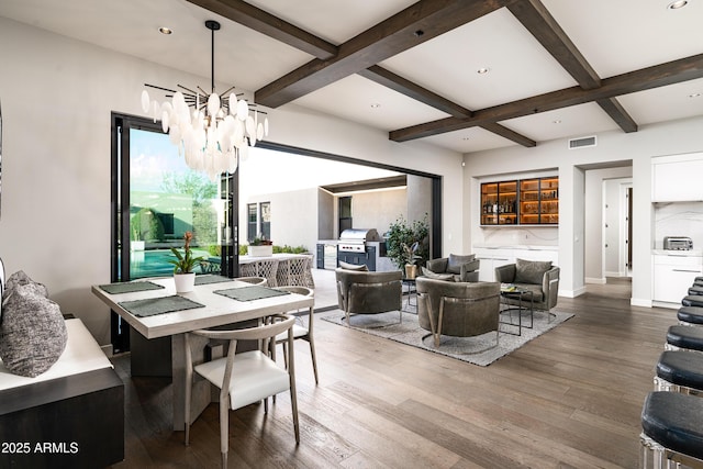 dining room with visible vents, beamed ceiling, wood finished floors, a notable chandelier, and coffered ceiling