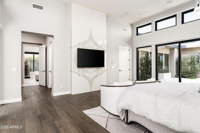 bedroom featuring visible vents, a towering ceiling, and wood finished floors