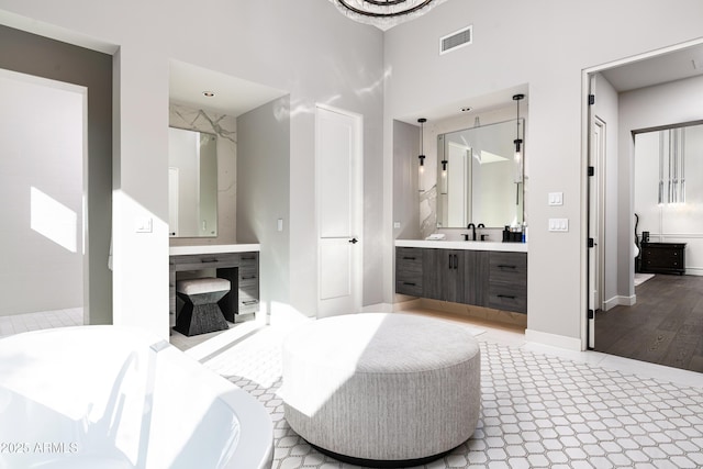 bathroom featuring visible vents, a freestanding bath, vanity, and baseboards