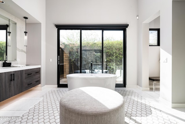 bathroom with tile patterned floors, a freestanding bath, vanity, and baseboards