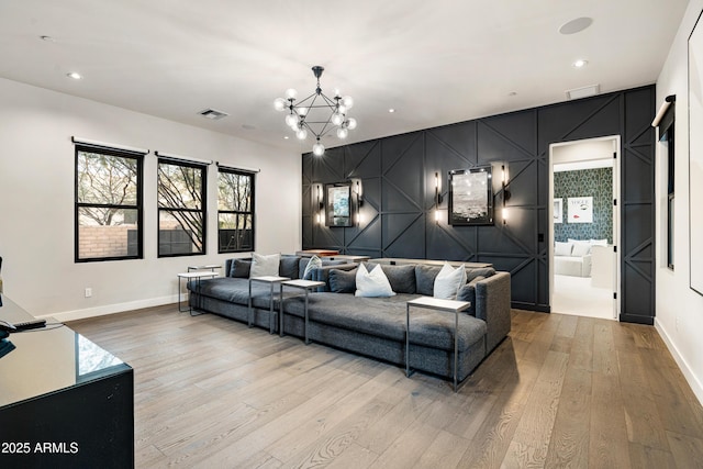 living area featuring visible vents, light wood-style flooring, baseboards, and an inviting chandelier