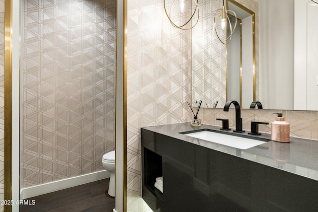 bathroom featuring decorative backsplash, toilet, baseboards, and wood finished floors