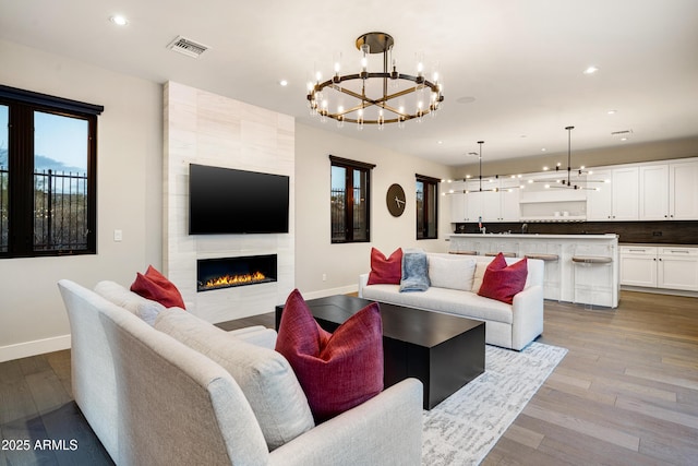 living area with a fireplace, visible vents, dark wood-style flooring, and baseboards