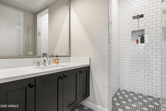 full bath with vanity, baseboards, and tiled shower