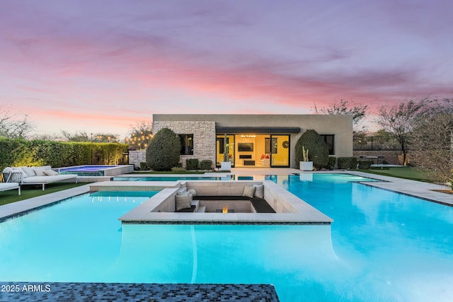 pool at dusk with a patio area, an outdoor living space, a fenced in pool, and an in ground hot tub