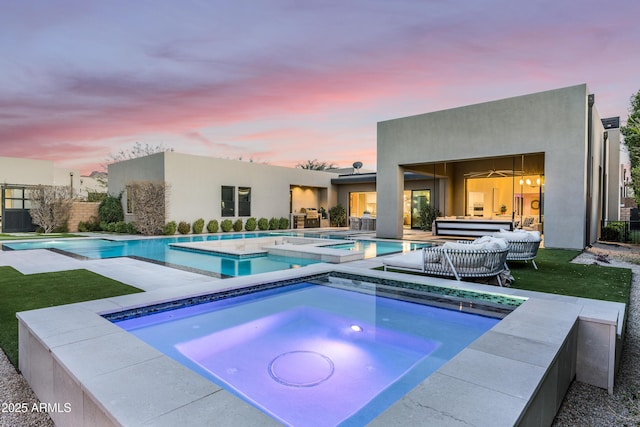 pool at dusk with an in ground hot tub, a patio area, and an outdoor pool